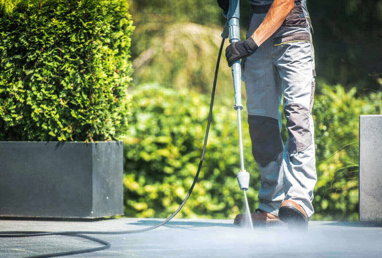 A field technician pressure washing a path